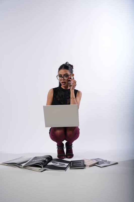 Crouching with a laptop and glasses, papers on the floor