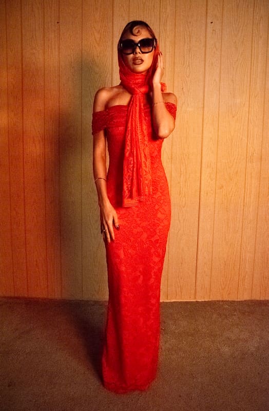 Full-length in a red lace dress and head scarf with sunglasses, wood-panelled wall