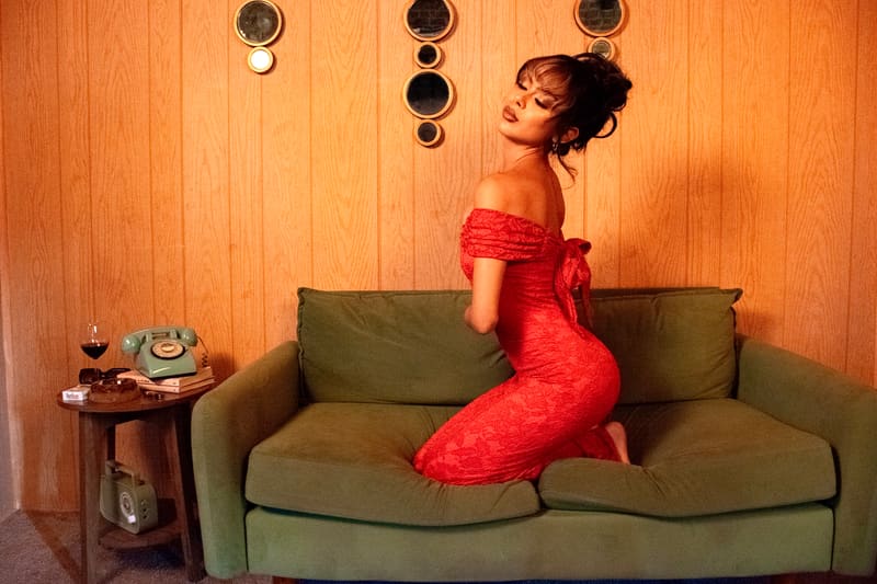 Kneeling on a green sofa in a red dress, looking back