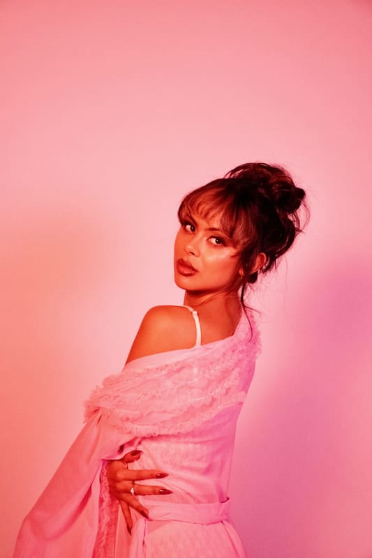 Seated portrait in pink lace against a pink backdrop